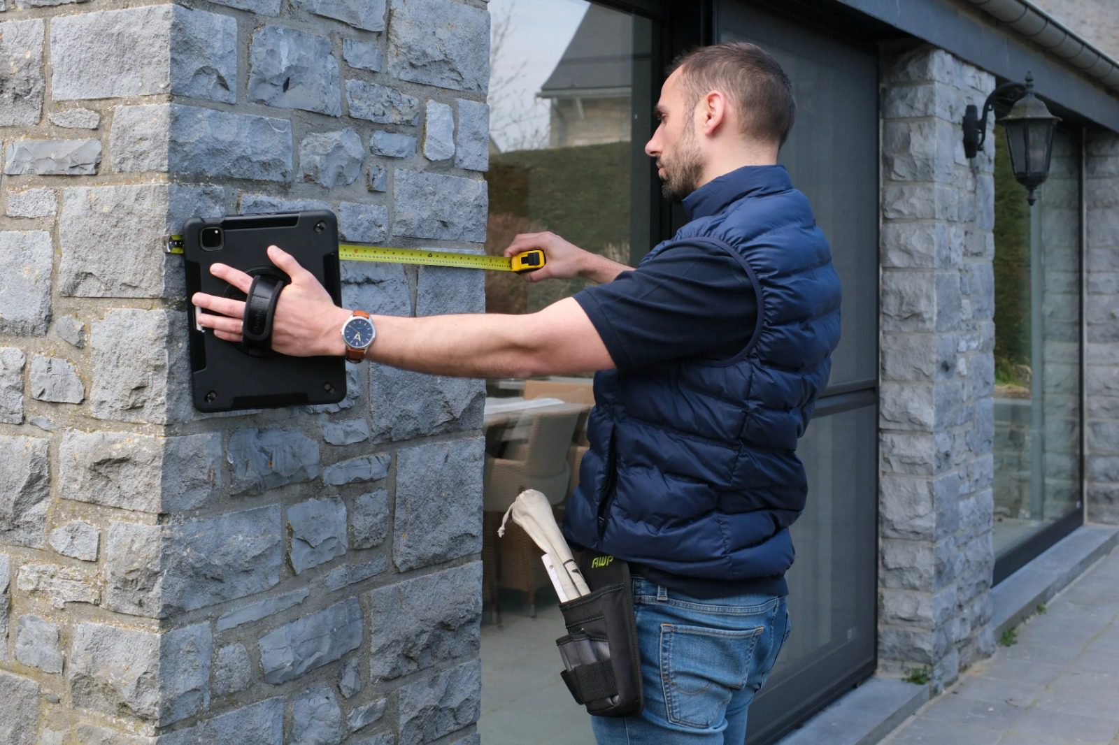 Auditeur agréé mesurant une façade en pierre lors d'un Audit Logement en Wallonie